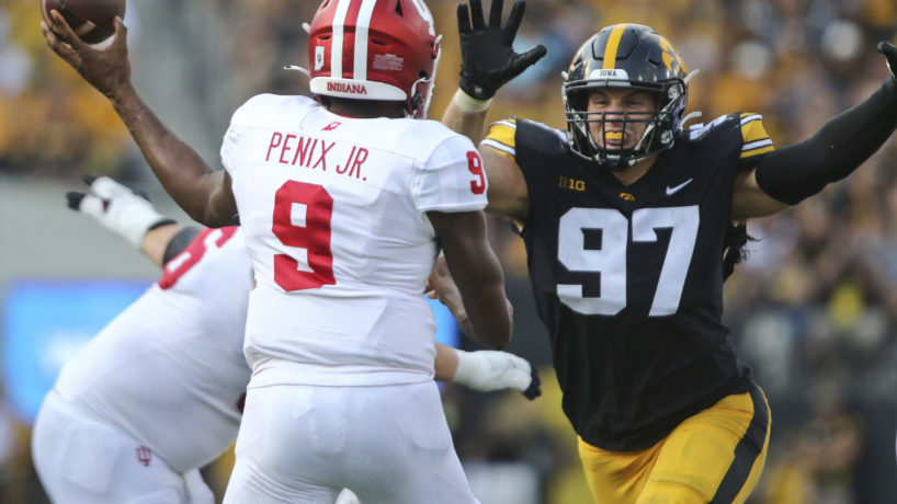 Michael Pennix Jr. throwing football with Iowa defender running at him