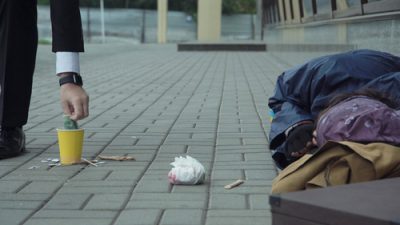 Man gives money to homeless man on street