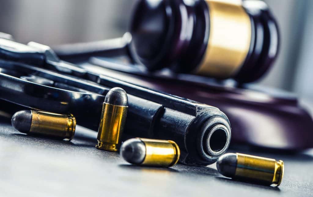 pistol and bullets laying infront of a gavel