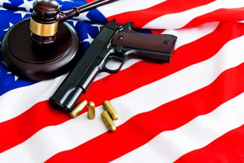 Gun with bullets and a gavel on top of an American flag