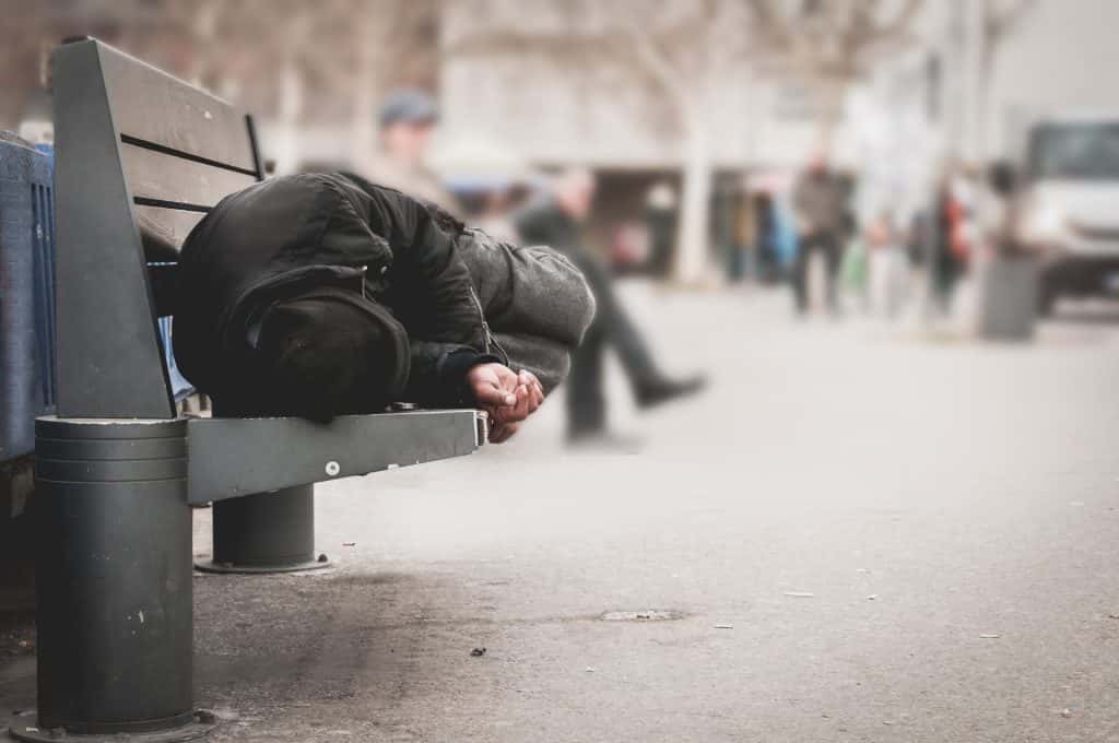 Homeless man sleeps on a bench