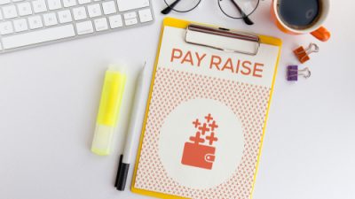 Office Supplies and Clipboard with "Pay Raise" Written on it