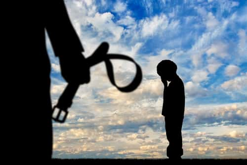 silhouette of a child with parent holding belt in background