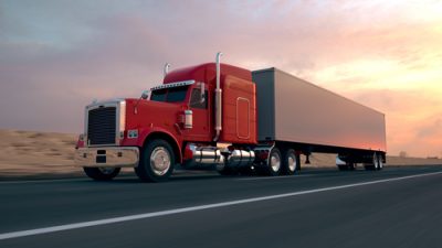 Red truck on highway with sunset in background