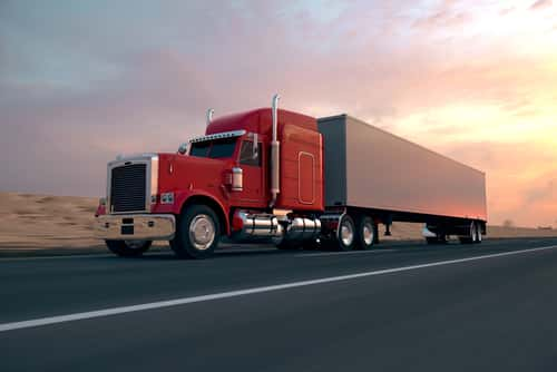 Red truck on highway with sunset in background