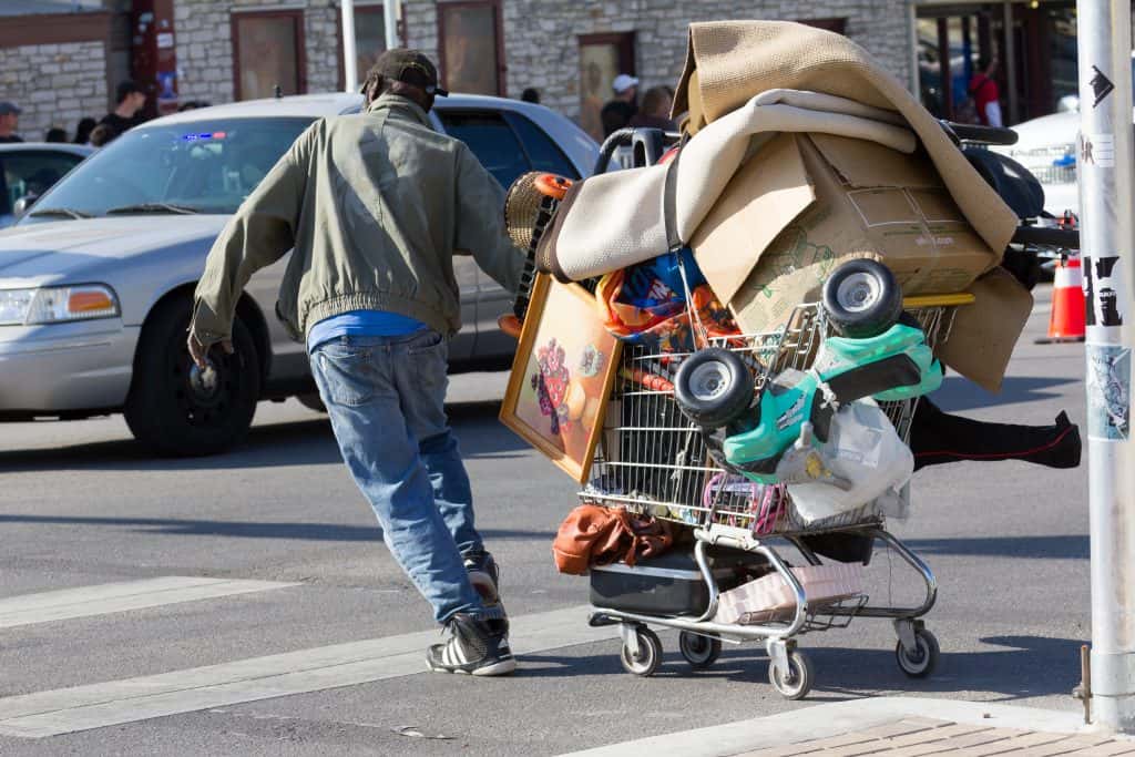 Homeless person pulling shopping cart full of stuff