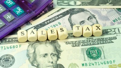 Money with block letters spelling "Sales Tax"