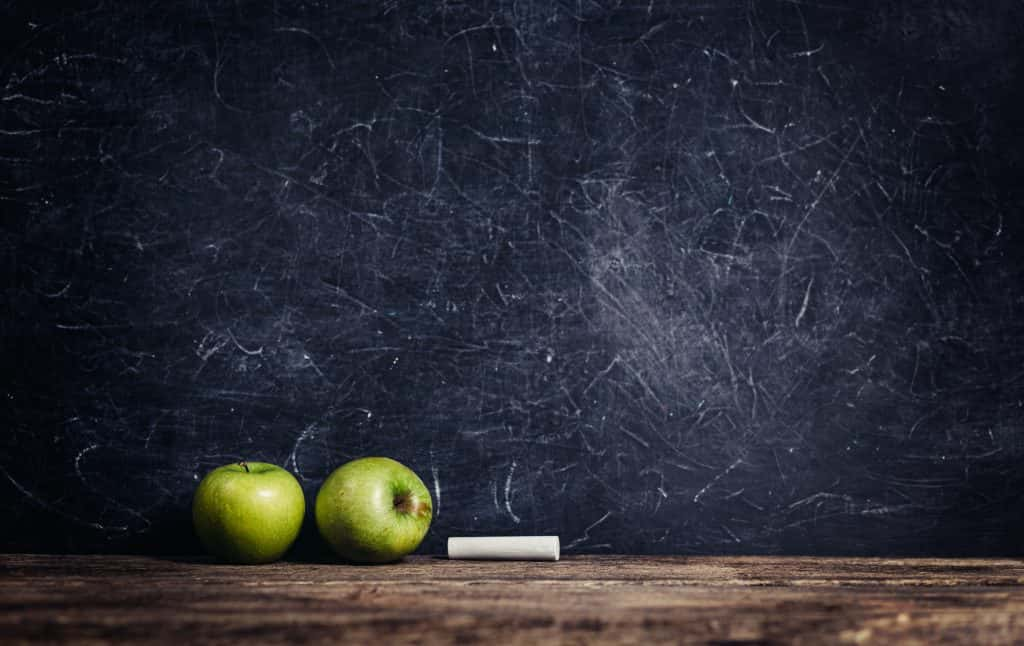 black board with apples depicting a classroom.