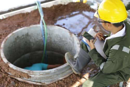 Plumbers working in open well