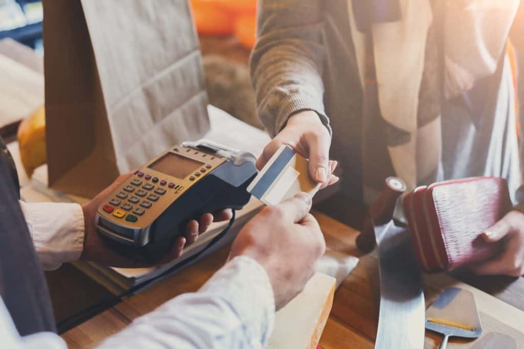 A person swiping a credit card through a credit card reader