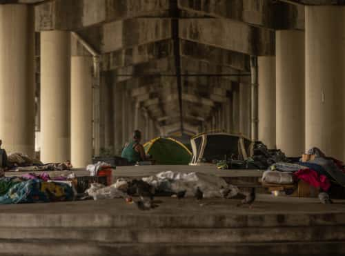 Woman with tent under bridge