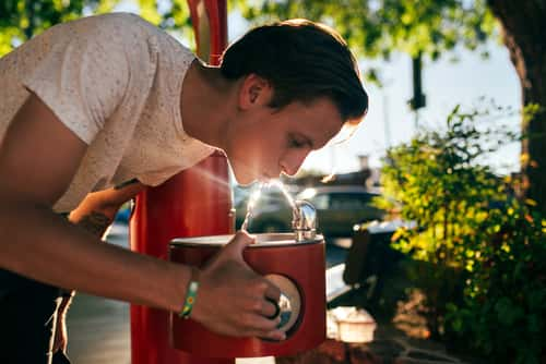 Man drinking out of water fountain