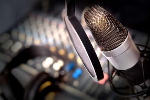 Image of a microphone with an audio console in the background