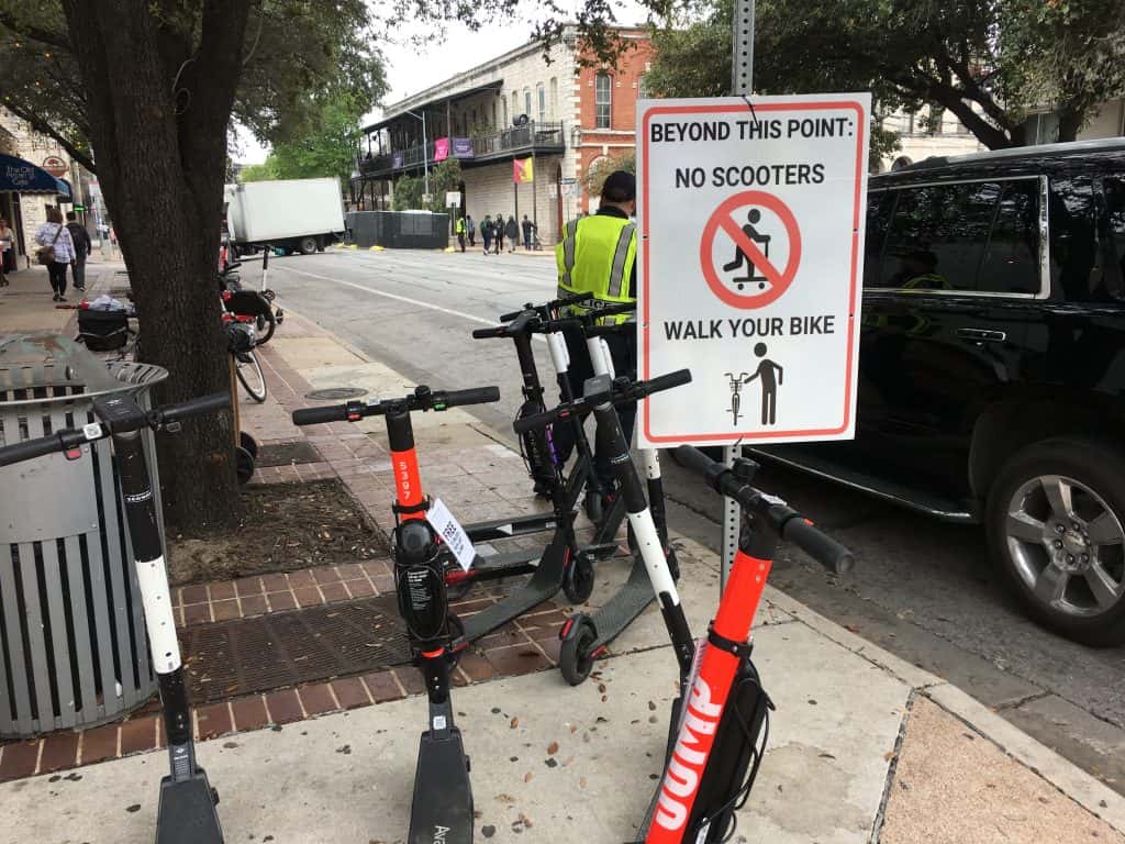Dockless electric scooters near a prohibited sign in downtown Austin during SXSW 2019