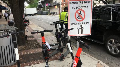 Dockless electric scooters near a prohibited sign in downtown Austin during SXSW 2019