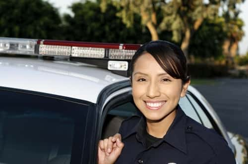 Female Police officer standing by patrol car