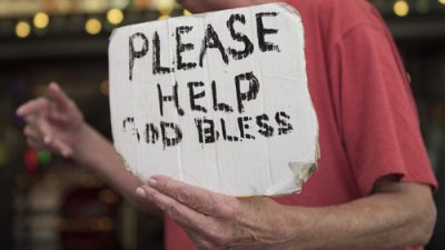 Homeless Woman Holding Sign saying "Please Help God Bless"