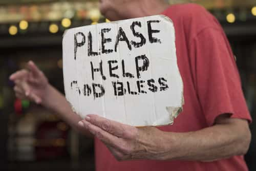 Homeless Woman Holding Sign saying "Please Help God Bless"