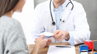 Doctor handing a prescription to patient