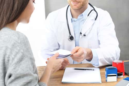 Doctor handing a prescription to patient