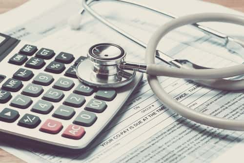 Calculator on top of medical bill with stethoscope