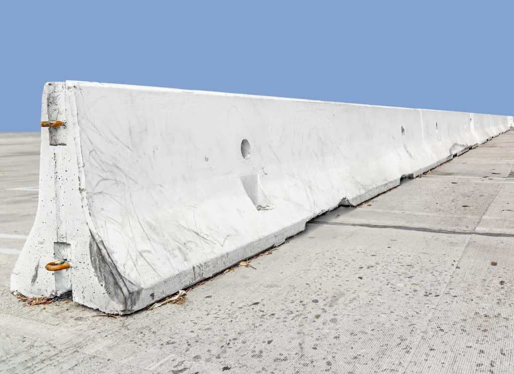 Long concrete traffic barrier, perspective view.Rough texture white stone safety barrier.Sloping surface, f-shape design.Nice fo