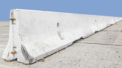 Long concrete traffic barrier, perspective view.Rough texture white stone safety barrier.Sloping surface, f-shape design.Nice fo