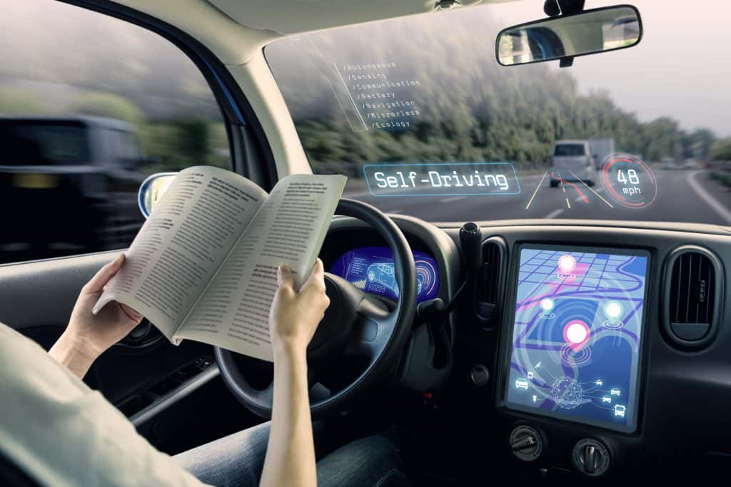 woman reading magazine while driverless car drives car