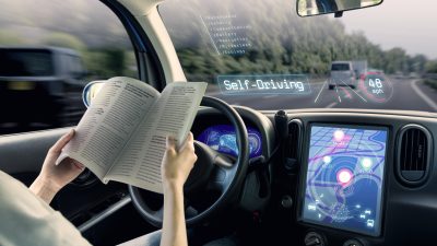 woman reading magazine while driverless car drives car
