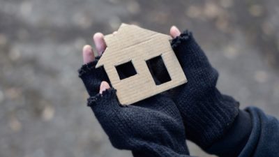 homeless man holding cardboard cut out of a house