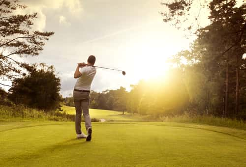 Man swinging golf club on course