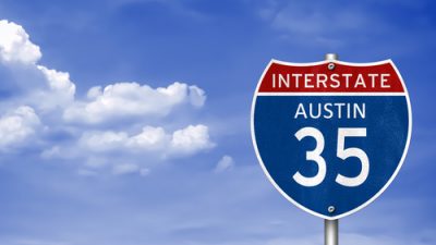 Interstate 35 to Austin sign in front of a blue sky and clouds