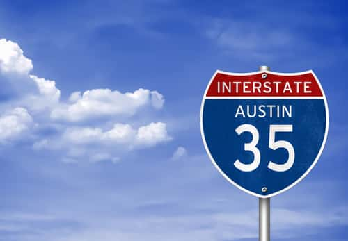 Interstate 35 to Austin sign in front of a blue sky and clouds