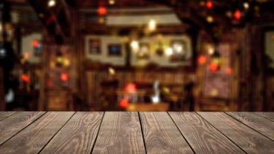 Blank wooden table top in front of abstract blurred restaurant lights