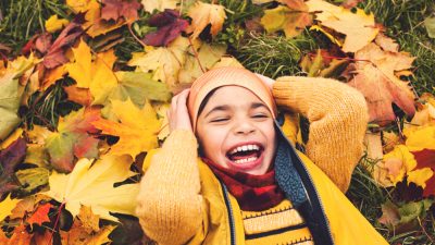 Child playing in autumn leaves