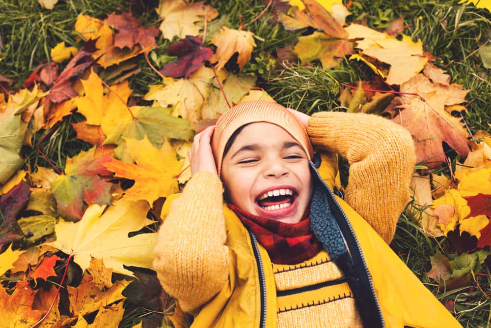 Child playing in autumn leaves