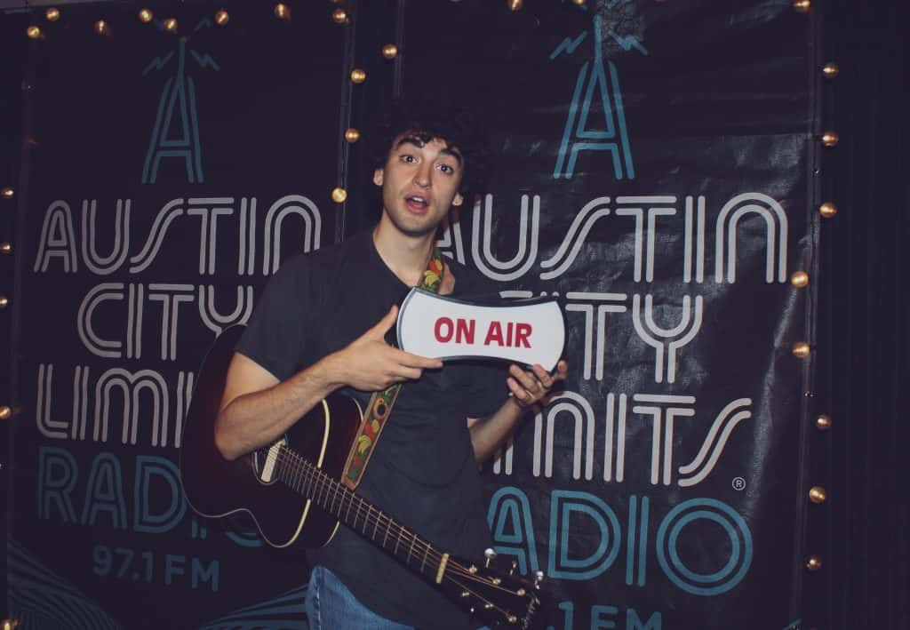 Adam Melchor holding "on-air" sign