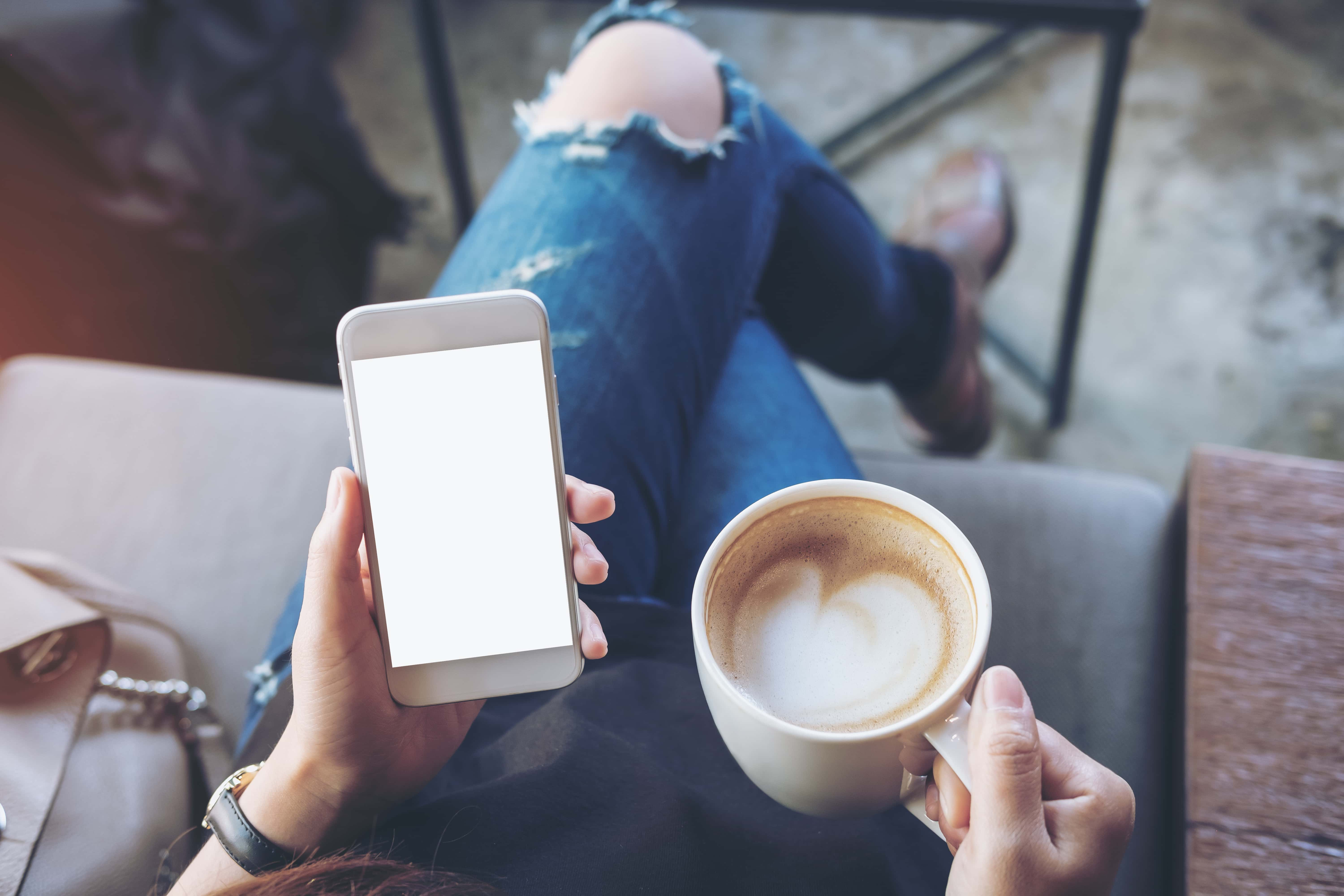 person holding phone and coffee