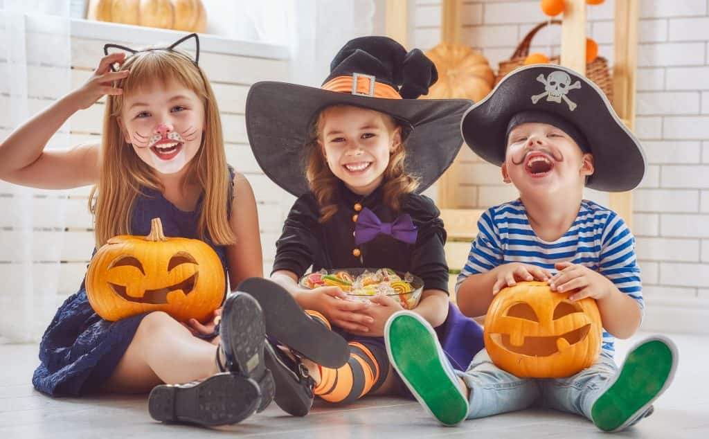 Kids laughing in Halloween costumes eating candy