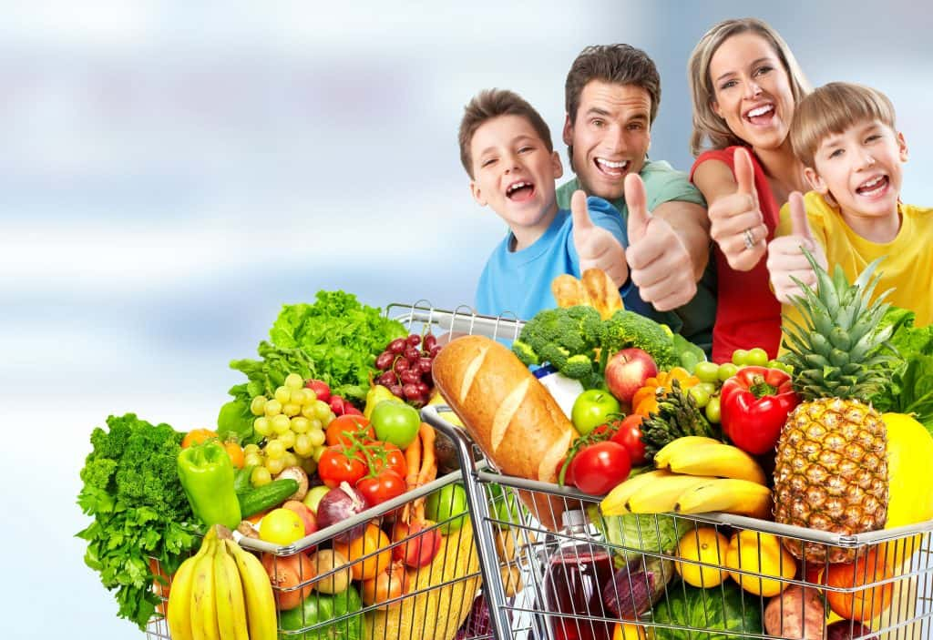 Shutterstock image of a family in the grocery store with thumbs up and a cart full of groceries.