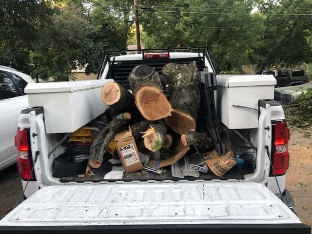 A truck filled with chopped up tree branches.
