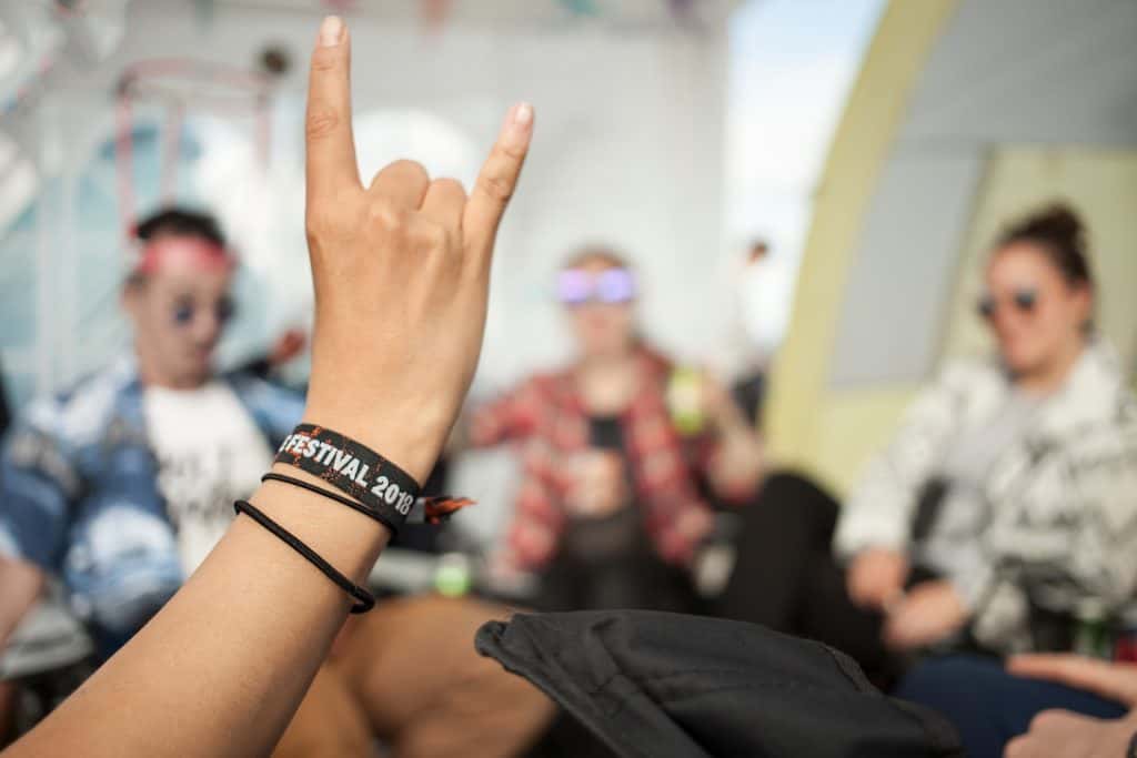 Guy holing hand up with rock on sign and wristband that says festival 2018