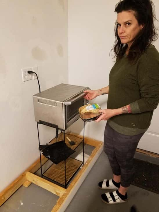 Deb in her kitchen with socks and a sweater.