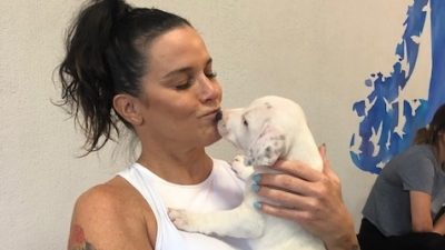 Deb kissing a puppy for puppy yoga.