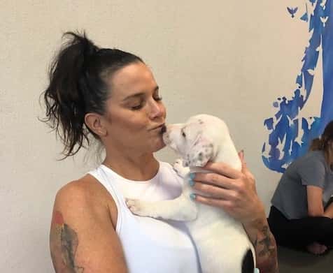 Deb kissing a puppy for puppy yoga.