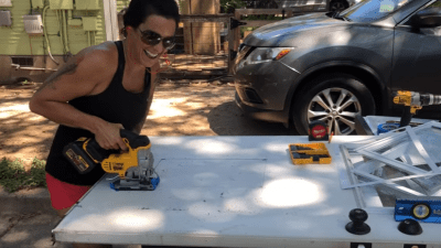 Deb with a saw in front of her house.