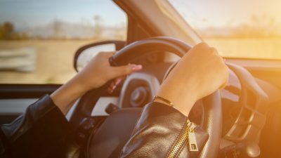 A lady with hands on the steering wheel.