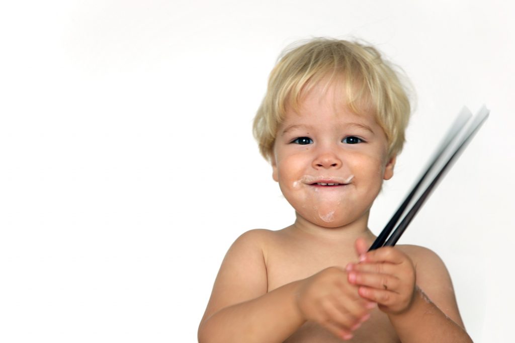 A kid playing with chopsticks.