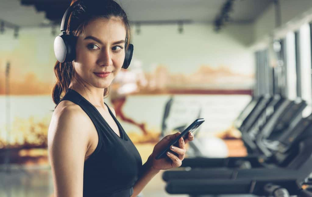 A lady in the gym looking suspicious with her headphones up.