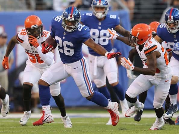 Saquon Barkley #26 of the New York Giants carries the ball as Damarious Randall #23 of the Cleveland Browns